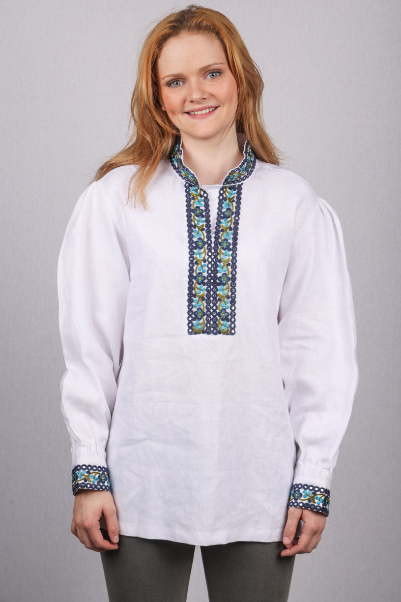 Kritthvit bomullsskjorte med nydelige detaljer på hals og ermene, med brodert bånd i nydelige blå nyanser. Skjorten kan brukes til forskjellige festdrakter og bunad. Denne skjorten kan også få med svart brodert bånd.