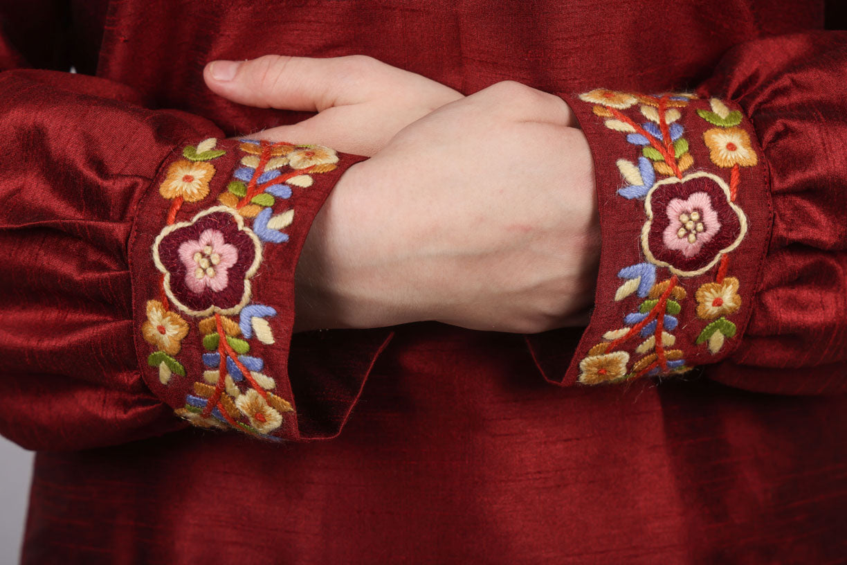 Bunadskjorte i 100% rawsilke med håndbroderte detaljer på krage og ermene. Ermene og kragen er brodert med garn og motiver av norske blomster. Detaljer på ermene