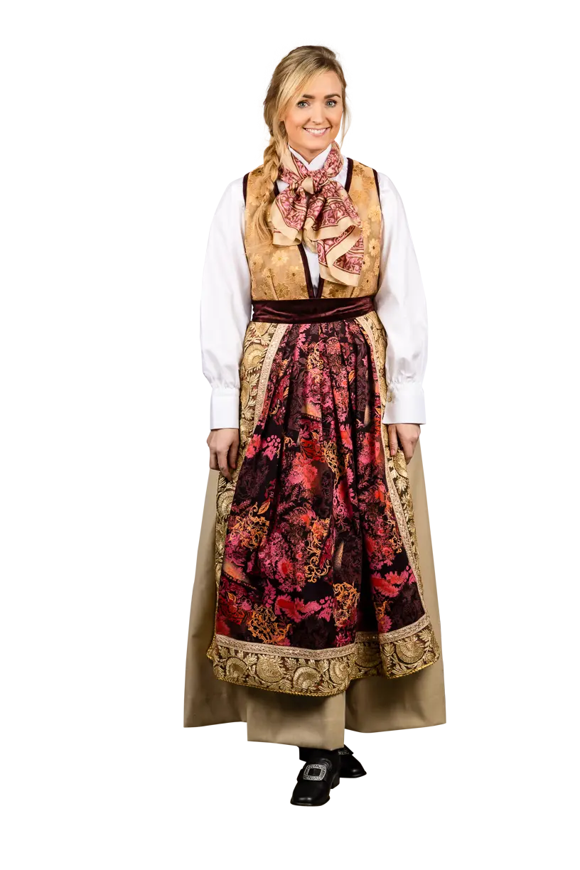Festdrakt Gullstakken er inspirert av vakre høstfarger. Stakken er i lys beige ullstoff, som er lett men varm, kantet med fløyel. Livet er i silke. Håndbrodert skjorte i rød silke.